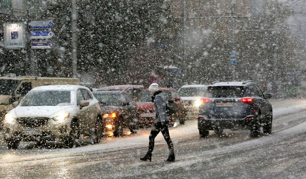 Женщина переходит улицу во время снегопада в Красноярске - Sputnik Afrique