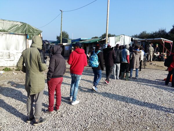 Des réfugiés attendent la distribution du repas à l’entrée de la Jungle Des réfugiés attendent la distribution du repas à l’entrée de la Jungle - Sputnik Afrique