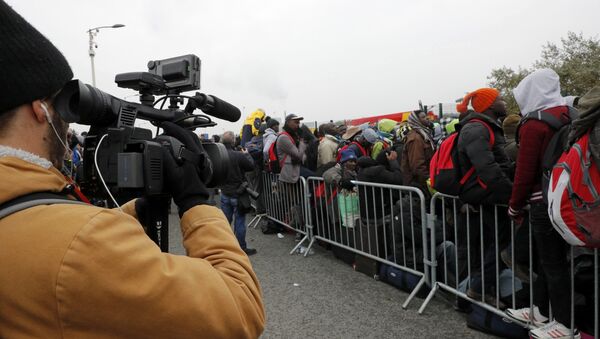 A TV cameraman films as migrants with their belongings queue at the start of their evacuation and transfer to reception centers in France, and the dismantlement of the camp called the Jungle in Calais, France, October 24, 2016. - Sputnik Afrique