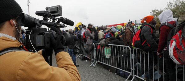 A TV cameraman films as migrants with their belongings queue at the start of their evacuation and transfer to reception centers in France, and the dismantlement of the camp called the Jungle in Calais, France, October 24, 2016. - Sputnik Afrique
