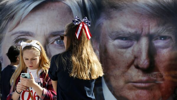 People pause near a bus adorned with large photos of candidates Hillary Clinton and Donald Trump before the presidential debate. - Sputnik Afrique