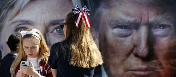 People pause near a bus adorned with large photos of candidates Hillary Clinton and Donald Trump before the presidential debate. - Sputnik Afrique
