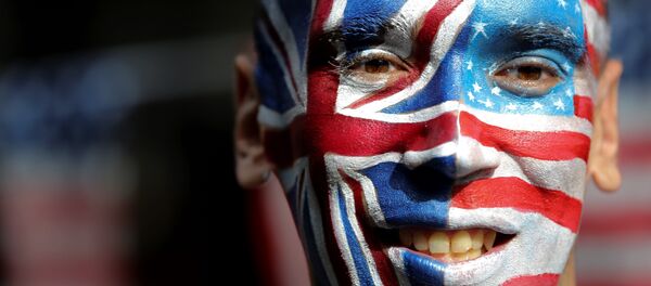 An activist with a face painted with the British Union Flag (L) and the US flag (R) poses in front of a Stop Trump battle bus in London on September 21, 2016 in a campaign run by campaign group Avaaz to mobilise US expatriots in the UK to register to vote in the US presidential election. Voters are set to go to the polls to elect the 45th president of the US on November 8, 2016. - Sputnik Afrique