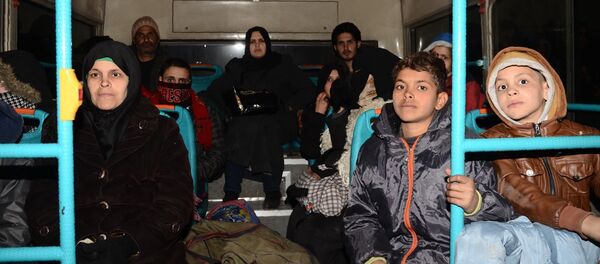 Syrian families, from various eastern districts of Aleppo, are evacuated by bus through Sheikh Maqsud, a Kurdish-controlled enclave between the government-held west of Aleppo and the east, on November 27, 2016 - Sputnik Afrique