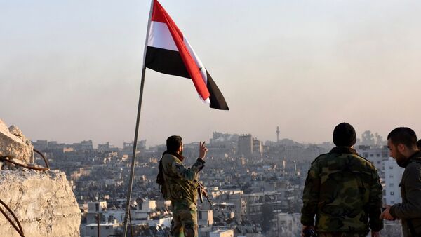 A Syrian government soldier gestures a v-sign under the Syrian national flag near a general view of eastern Aleppo after they took control of al-Sakhour neigbourhood in Aleppo, Syria in this handout picture provided by SANA on November 28, 2016. - Sputnik Afrique