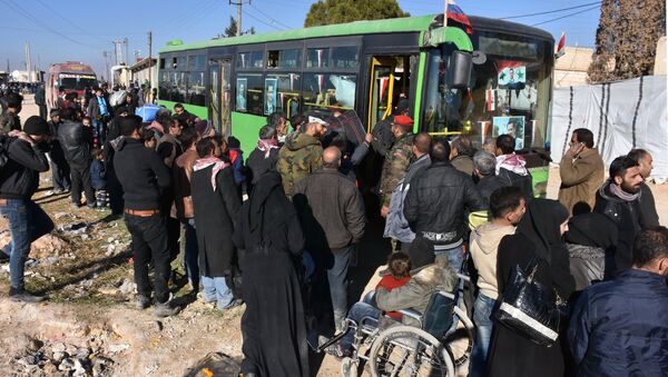 Syrian residents fleeing the violence, queue as they board a bus at a checkpoint, manned by pro-government forces, in the village of Aziza on the southwestern outskirts of the northern Syrian city of Aleppo on December 9, 2016 - Sputnik Afrique