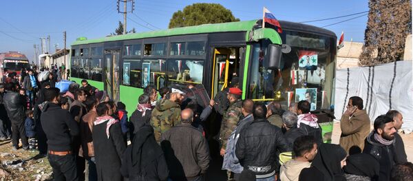Syrian residents fleeing the violence, queue as they board a bus at a checkpoint, manned by pro-government forces, in the village of Aziza on the southwestern outskirts of the northern Syrian city of Aleppo on December 9, 2016 - Sputnik Afrique