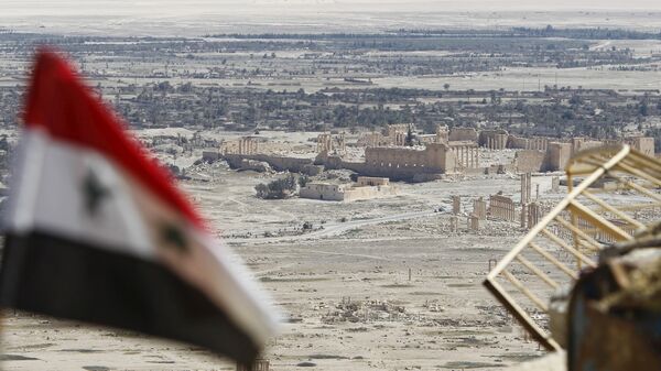 A Syrian national flag flutters as the ruins of the historic city of Palmyra are seen in the background, in Homs Governorate, Syria April 1, 2016. - Sputnik Afrique