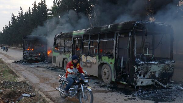A man on a motorcycle drives past burning buses while en route to evacuate ill and injured people from the besieged Syrian villages of al-Foua and Kefraya, after they were attacked and burned, in Idlib province, Syria December 18, 2016 - Sputnik Afrique