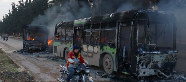 A man on a motorcycle drives past burning buses while en route to evacuate ill and injured people from the besieged Syrian villages of al-Foua and Kefraya, after they were attacked and burned, in Idlib province, Syria December 18, 2016 - Sputnik Afrique