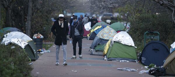 People walk by a makeshift camp set by migrants, on December 16, 2016 in Saint-Denis, a northern Paris' suburb. - Sputnik Afrique