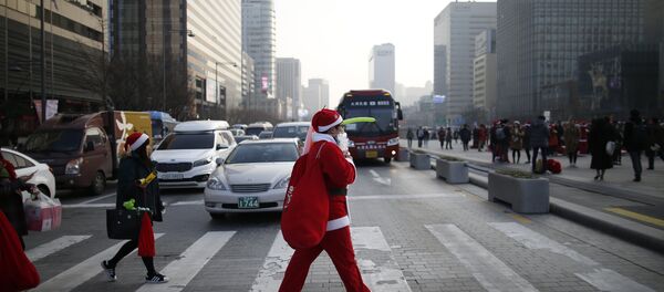 A man dressed as Santa Claus walks on zebra crossing during a Christmas charity event in central Seoul, South Korea, December 24, 2015 - Sputnik Afrique