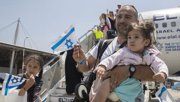 Newly arrived Jewish immigrants coming from France hold Israeli flags as they step off the plane upon their arrival at the Ben Gurion International Airport near Tel Aviv on July 20, 2016. - Sputnik Afrique