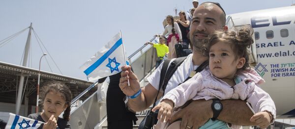 Newly arrived Jewish immigrants coming from France hold Israeli flags as they step off the plane upon their arrival at the Ben Gurion International Airport near Tel Aviv on July 20, 2016. - Sputnik Afrique
