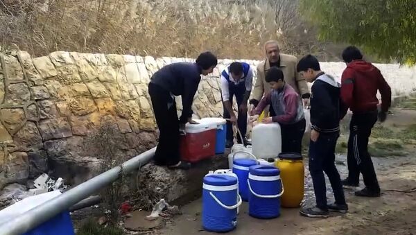 This frame grab from video provided By Yomyat Kzefeh Hawen Fi Dimashq (Diary of a Mortar Shell in Damascus), a Damascus-based media outlet that is consistent with independent AP reporting, shows Syrian residents filling up buckets and gallons of spring water from a pipe on the side of the road, in Damascus, Syria - Sputnik Afrique