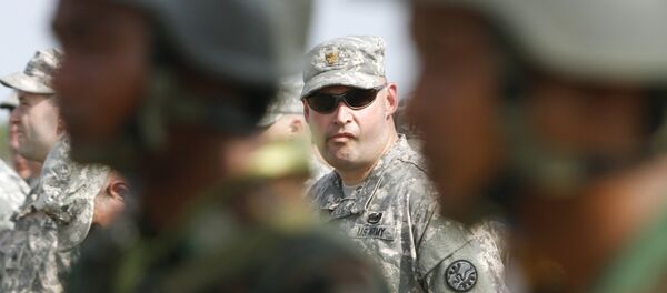 U.S. army soldier, center, is framed by Cambodian soldiers during a U.S.-backed peacekeeping exercise dubbed Angkor Sentinel 2014 at the Cambodian tank command headquarters in Kampong Speu province, 60 kilometers (37 miles) west of Phnom Penh, Cambodia, Monday, April 21, 2014. The U.S. and Cambodia on Monday commenced Angkor Sentinel, an annual military exercise designed to promote regional peace and security. (AP Photo/Heng Sinith) - Sputnik Afrique