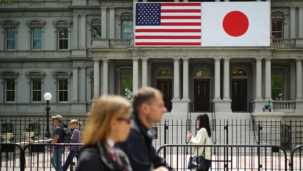 Les piétons passent devant les drapeaux des États-Unis et du Japon sur le bâtiment du bureau d'Eisenhower à côté de la Maison Blanche, le 27 avril 2015 à Washington, DC - Sputnik Afrique