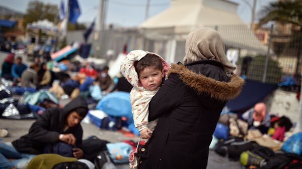 A Syrian woman holds her child at the port of Chios on April 3, 2016 as refugees and migrants who broke out from Chios detention camp, stand in the port of the city. - Sputnik Afrique
