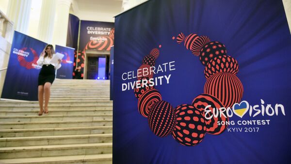 An employee walks past a placard bearing the official logo of the Eurovision Song Contest 2017 depicting a traditional Ukrainian necklace with the slogan reading Celebrate Diversity, on January 31, 2017 in Kiev. - Sputnik Afrique