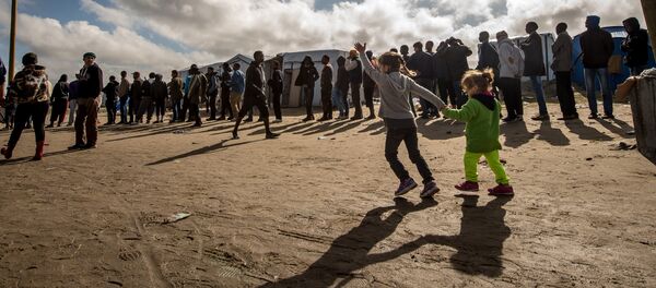 Migrants queue to get food at a site dubbed the New Jungle, where some 3,000 people have set up camp -- most seeking desperately to get to England, in Calais on September 19, 2015. - Sputnik Afrique