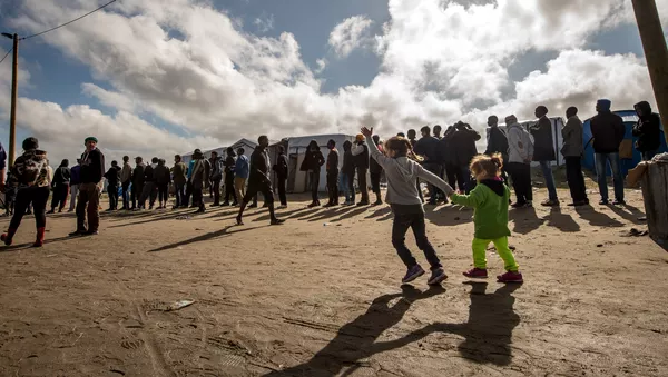 Migrants queue to get food at a site dubbed the New Jungle, where some 3,000 people have set up camp -- most seeking desperately to get to England, in Calais on September 19, 2015. - Sputnik Afrique