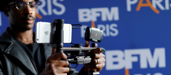 A video journalist uses an Apple iPhone 7 Plus smart phone to film during a press conference for the launching of the news channel, BFM Paris, in Paris, France, October 13, 2016 - Sputnik Afrique