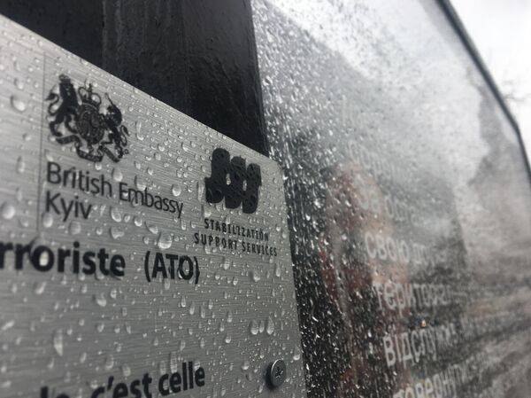 Une image de l'exposition Displaced accompagnée de l'emblème de l'ambassade britannique à Kiev - Sputnik Afrique