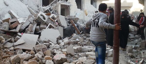 People walk past a building that was reportedly targeted by the US-led coalition, in the Islamic State (IS) controlled Syrian city of Raqqa on November 11, 2014. - Sputnik Afrique