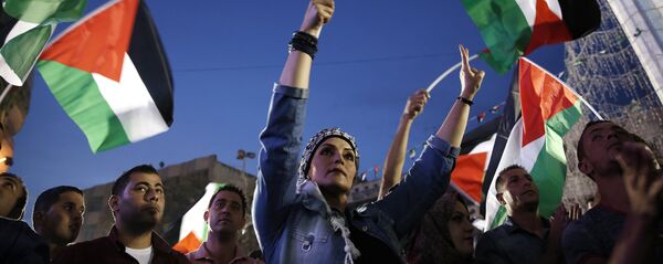 Palestinians wave their national flags as they watch a live-screening of president Mahmud Abbas' speech followed by the raising of the Palestinian flag at the United Nations headquarters in New York, on September 30, 2015 in the city of Ramallah - Sputnik Afrique