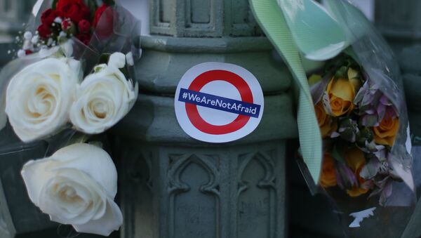 Des bouquets de fleurs et un autocollant montrant le logo du métro de Londres et les mots «Nous n'avons pas peur» en l'honneur des victimes de l'attentat terroriste du 22 mars sont représentés dans le centre de Londres le 23 mars 2017. - Sputnik Afrique