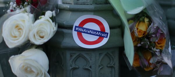 Des bouquets de fleurs et un autocollant montrant le logo du métro de Londres et les mots «Nous n'avons pas peur» en l'honneur des victimes de l'attentat terroriste du 22 mars sont représentés dans le centre de Londres le 23 mars 2017. - Sputnik Afrique