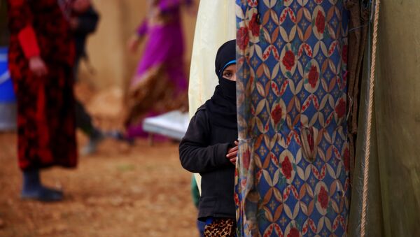 A displaced Syrian woman, who fled her hometown due to clashes between regime forces and the Islamic State (IS) group, stands outside a tent in Kharufiyah, 18 kilometres south of Manbij, on March 4, 2017. - Sputnik Afrique