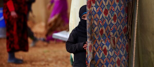 A displaced Syrian woman, who fled her hometown due to clashes between regime forces and the Islamic State (IS) group, stands outside a tent in Kharufiyah, 18 kilometres south of Manbij, on March 4, 2017. - Sputnik Afrique