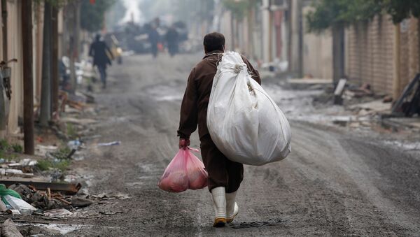 Un homme irakien porte des marchandises de l'aide humanitaire dans le district d'Al Ghizlane alors que la lutte contre les terroristes de l'État islamique se poursuit à Mosul, en Irak - Sputnik Afrique