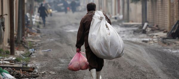 Un homme irakien porte des marchandises de l'aide humanitaire dans le district d'Al Ghizlane alors que la lutte contre les terroristes de l'État islamique se poursuit à Mosul, en Irak - Sputnik Afrique