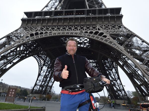 Arnold Schwarzenegger, ex-gouverneur de Californie et acteur américain, pose avec un vélo devant la caméra sous la Tour Eiffel avec les pouces levés après avoir fait le tour de Paris à vélo le 6 décembre 2015. - Sputnik Afrique