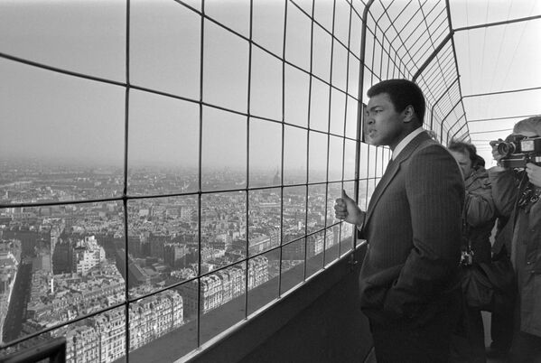 Muhammad Ali, champion du monde poids lourds américain (au centre), visite la Tour Eiffel le 5 mars 1976. - Sputnik Afrique
