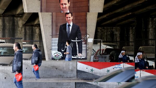 Des habitants de Damas devant une affiche représentant le président syrien Bachar el-Assad - Sputnik Afrique