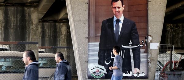 Des habitants de Damas devant une affiche représentant le président syrien Bachar el-Assad - Sputnik Afrique