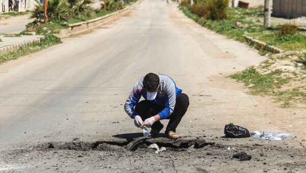 A Syrian man collects samples from the site of a suspected toxic gas attack in Khan Sheikhun, in Syria’s northwestern Idlib province, on April 5, 2017. - Sputnik Afrique