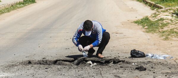 A Syrian man collects samples from the site of a suspected toxic gas attack in Khan Sheikhun, in Syria’s northwestern Idlib province, on April 5, 2017. - Sputnik Afrique