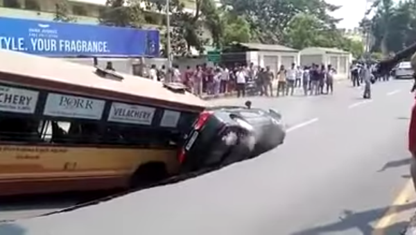Un bus et une voiture s’enlisent dans un immense nid de poule en Inde - Sputnik Afrique