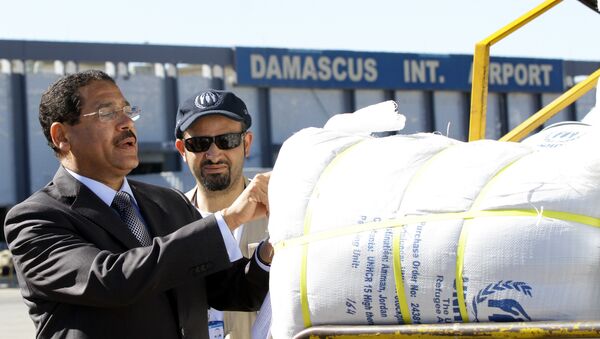 United Nation's Refugee Agency (UNHCR) representative in Syria, Tarik Kurdi (L) inspects parcels of emergency relief provided by the UNHCR after they were unloaded from a cargo aircraft on February 13, 2014 at Damascus' International Airport. - Sputnik Afrique