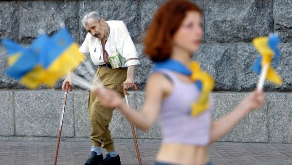 An elderly invalid man (back) sings and dances to attract the attention of passers-by, while a girl sales Ukrainian national flags to make some money in downtown Kiev, 31 July 2003. - Sputnik Afrique