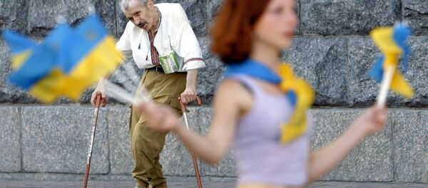 An elderly invalid man (back) sings and dances to attract the attention of passers-by, while a girl sales Ukrainian national flags to make some money in downtown Kiev, 31 July 2003. - Sputnik Afrique