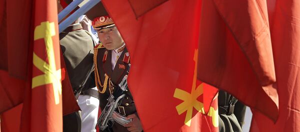 A North Korean military soldier peeps through his country's ruling party flags decorating the Ryomyong residential area, a collection of more than a dozen apartment buildings, ahead of its official opening ceremony on Thursday, April 13, 2017, in Pyongyang, North Korea. - Sputnik Afrique