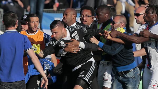 A security staff holds Lyon's goalkeeper Anthony Lopes (C) during scuffles at half-time between some of Lyon's players and Bastia supporters who invaded the pitch, during the French L1 football match Bastia (SCB) vs Lyon (OL) on April 16, 2017 in the Armand Cesari stadium in Bastia on the French Mediterranean island of Corsica. Before the match, dozens of Bastia fans invaded the pitch at their Armand Cesari stadium and attacked Lyon players as they warmed up for a French Ligue 1 game. - Sputnik Afrique