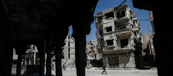 Syrians walk past damaged buildings on April 7, 2017, in the rebel-held town of Douma, on the eastern outskirts of Damascus. - Sputnik Afrique