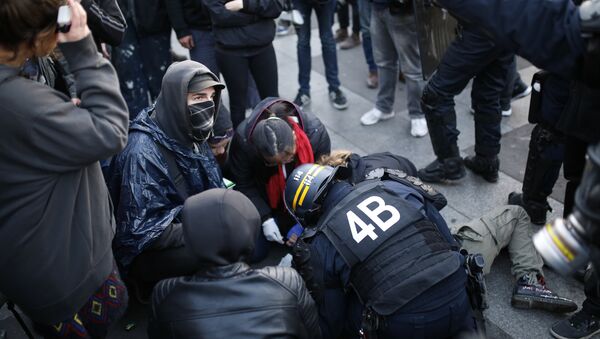 French anti-riot police forces tend to a demonstrator lying on the ground in Paris on April 23, 2017 following the announcement of the results of the first round of the Presidential election. - Sputnik Afrique