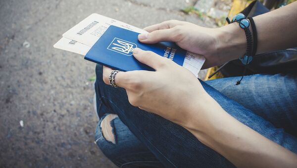 Девушка держит в руках украинский паспорт с билетами - Sputnik Afrique
